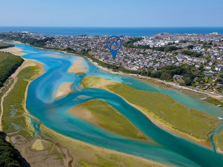 A view of a river flowing into the ocean with houses in the background at Newquay Tamarisk Lodge on the Gannel Newquay
