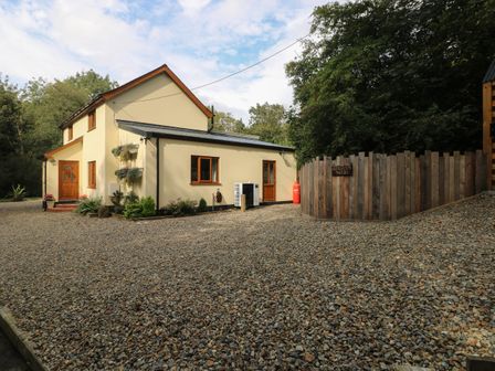 A gravel driveway with a two-story cream building and wooden fence at Rudbaxton Water in Rudbaxton near Haverfordwest