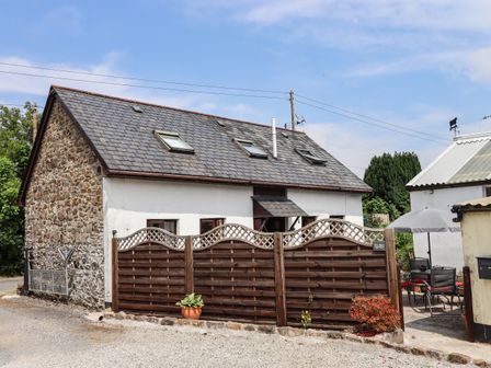 A stone and white house with skylights and a wooden fence in front at Northwood Barn in Okehampton