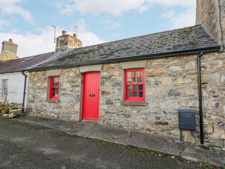 Stone house with red door and windows and a sloped roof at Frondeg Newport Pembrokeshire