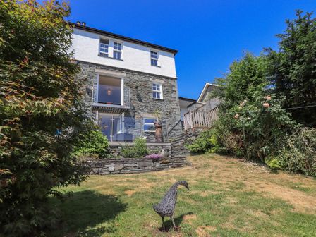 A stone and white house with a garden and metal bird sculpture at Timley Knott in Coniston