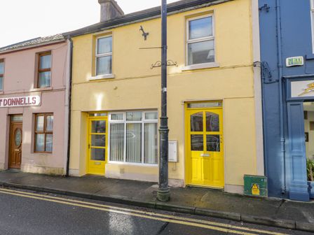 A street view with a yellow two-story building with two yellow doors and windows at Glebe House in Ballinrobe County Mayo