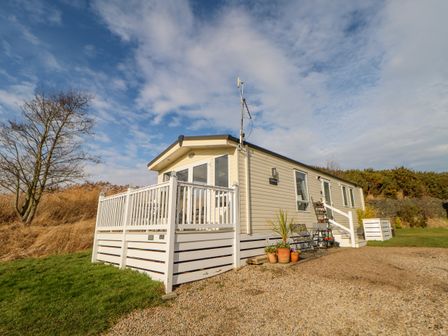 A single story mobile home with a white railing deck and plants outside at 46 Willowburn in Felton
