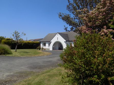A driveway leading to a white house with an arched entrance surrounded by grass and bushes at Brookfield in St Gennys near Wainhouse Corner