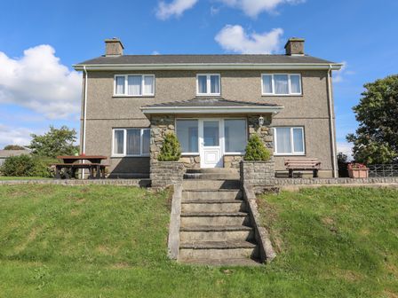 The front view of a two-story house with stone steps leading to the entrance at Gelli Gron Llanarmon near Y Ffor