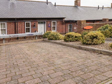 A brick paved driveway with no parking sign and bushes in front of a brick building with white doors and windows at Porters Rest in Whitby