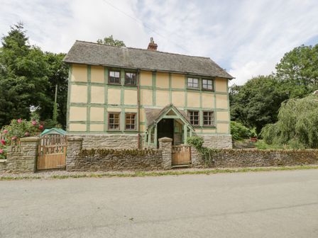 A two-story house with timber framing and a stone wall with wooden gates at The Old Rectory in Presteigne