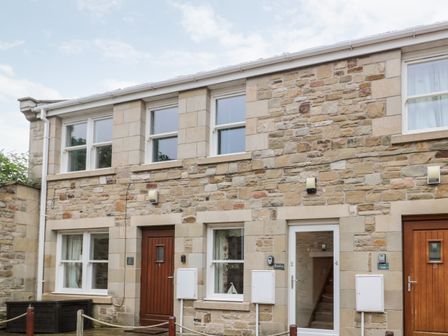 A stone house with multiple windows and wooden doors at 2 Apple Tree in Beadnell