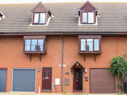 A brick townhouse with brown garage doors and windows at Harveys Holiday House in Hunstanton
