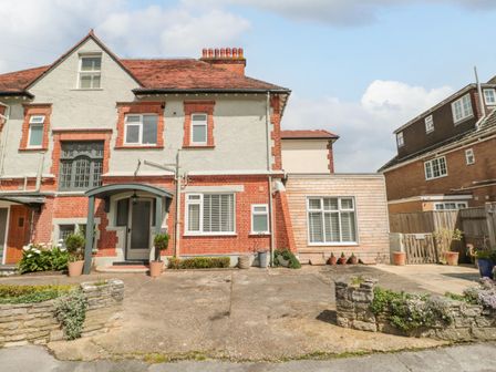 A semi detached house with a driveway and potted plants at The Anchorage in Bournemouth