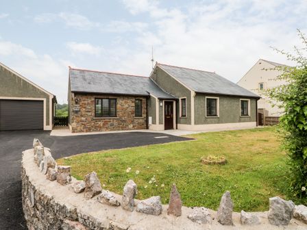 A single-story house with a stone wall and grass lawn at Timaru in Lamphey