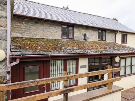 Exterior of a stone and plaster building with a moss-covered roof and windows at The Woodman in Nantmel near Rhayader