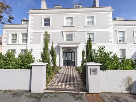 A white three-story residential building with a black and white tiled walkway leading to a black door at 66 3 Compass Point in Weymouth