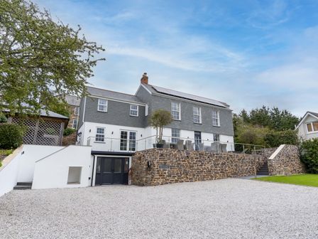 A two-story house with a stone patio and outdoor seating area at Chyvounder in St Agnes