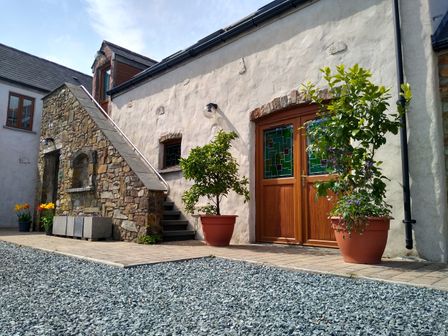 An exterior courtyard with stone steps wooden doors and potted plants at Cranny Bethesda near Narberth