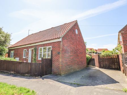 A single story brick house with a tiled roof and wooden fence at 1A Police House in Whitby
