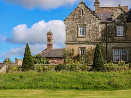 A stone house with windows and trimmed bushes in front at The Pavillion in Kirklinton near Longtown