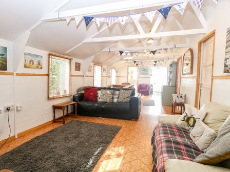 A living room with sofas a rug and bunting decorations at Suzanne's Beach Hut in Bacton near Walcott
