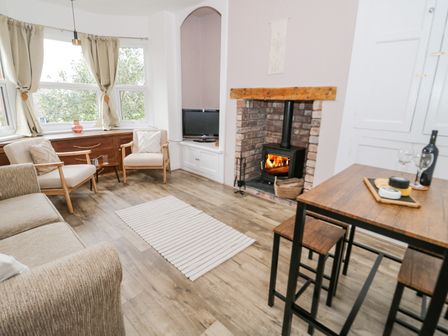 A living room with chairs a stove and a dining table at Ty Arth in Llandudno