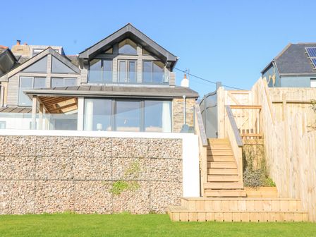 A modern house with glass balcony stone wall wooden stairs and fenced garden at Oakleigh in Blackawton