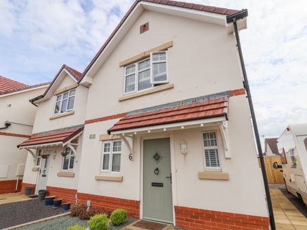 The front exterior of a pair of semi detached houses with tiled roofs and small gardens at 6 Cwrt Griffiths in Prestatyn