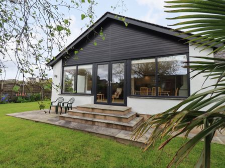 A backyard view of a house with large windows and steps leading to a patio at Pembroke in Cartmel