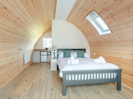 A bedroom with a bed a kitchenette and a skylight window at Carlton Manor Pod 10 in Aldbrough