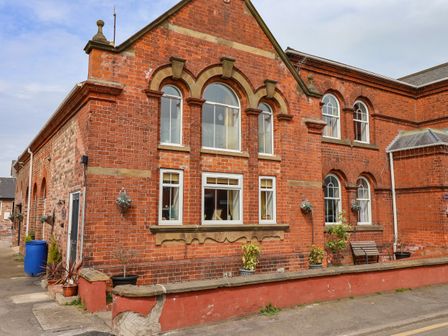 A red brick building with arched windows and potted plants outside at The Old Police House in Withernsea