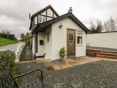 Exterior view of a cottage with a wooden door small window pathways steps and gravel area at Pool Cottage Staunton-on-Wye near Eardisley