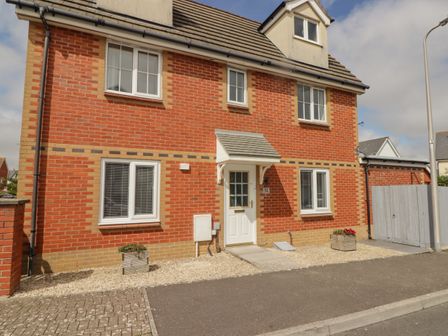A front view of a two-story red brick house with white windows and a white door at 12 Clos Yr Wylan in Barry