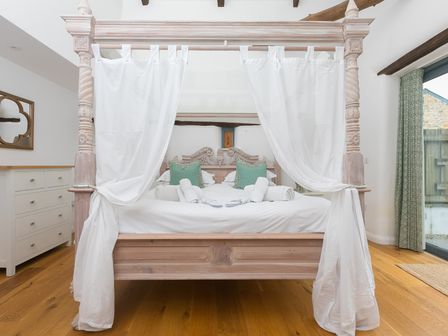 A bedroom with a four-poster bed and chest of drawers at Carines Barns - Wesley Barn, Cubert