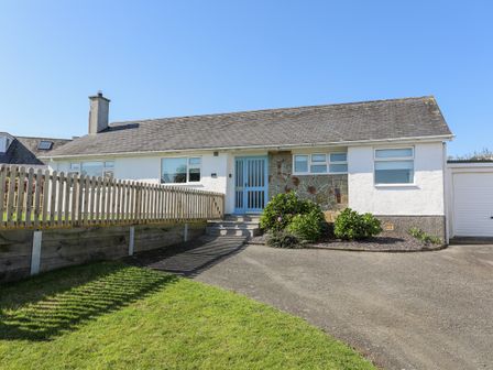 A single story house with a fenced garden driveway and garage at 7 Maes Awel in Abersoch