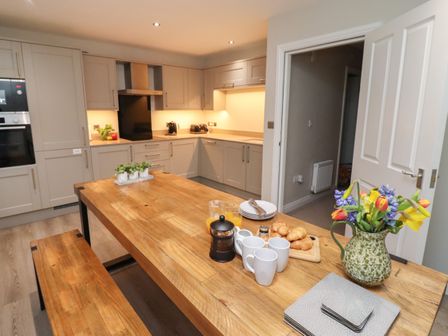 A kitchen with wooden dining table set with mugs croissants and flowers at Aurora Whitby
