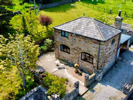 A stone house with a patio and garden area surrounded by green fields at The Coach House in Trelogan Hall Trelogan near Trelawnyd