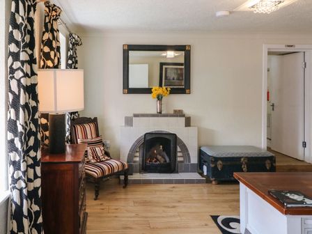 A living room with a tiled fireplace striped chair door lamp and curtains at Shoemaker's Rest in Ardgroom Village