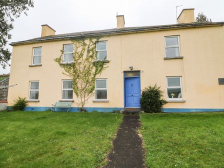 The front view of a two story house with a blue door a pathway and green lawn at The Bride Valley Farmhouse in Tallow County Waterford