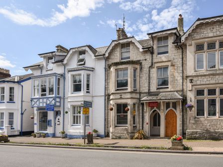 A street view of connected guest house and apartment buildings with hanging flower baskets at Apartment 1 Durham House in Beer