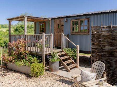 An outdoor hut with steps and planters at Spindleberry Hut in Piddletrenthide