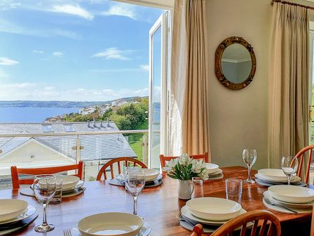 A dining room with a table set for dinner at Looe Island View in Downderry