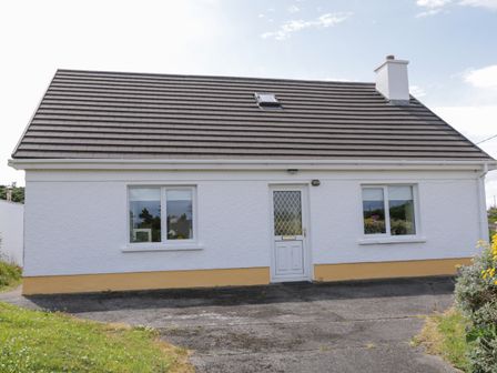 A single story white house with a dark roof two windows and a central door at Kincasslagh near Annagry County Donegal