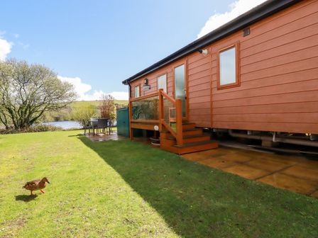 A garden with a duck near a patio and table next to a wooden cabin at Lake View 10 in Par
