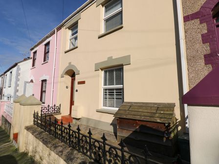 A row of terraced houses with iron fencing and a wooden box in front at Stones Throw in Tenby