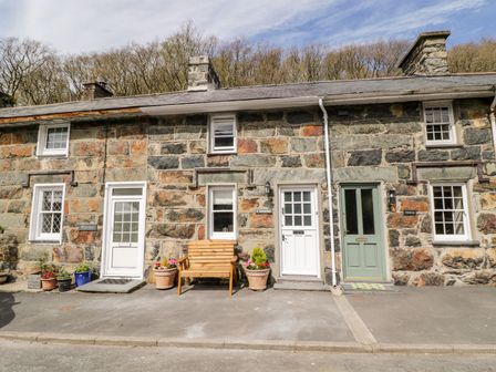 Stone cottages with white and green doors and potted plants outside at Henfro in Beddgelert