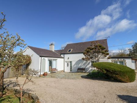A white house with a slate roof a gravel driveway and bushes at Llwyn Celyn in Edern near Morfa Nefyn
