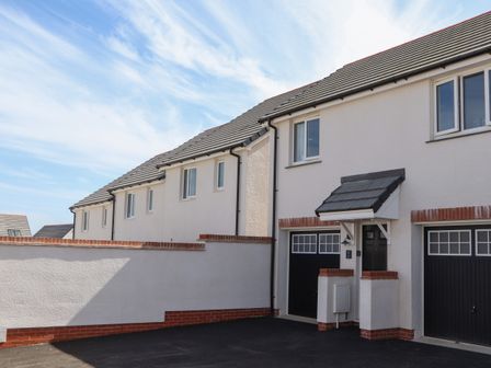 Exterior view of a row of modern houses with garages and a driveway at Trewhiddle Retreat in St Austell