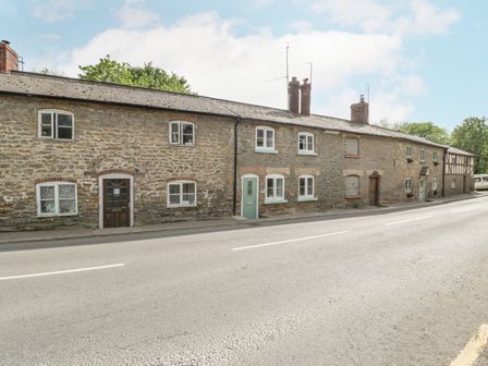 A row of stone cottages with multiple windows and doors along a road at 4 Wallflower Row in Mordiford near Hereford