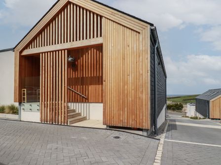 A modern house with wooden slats on the exterior and a paved driveway at 5 Longshore in Newquay