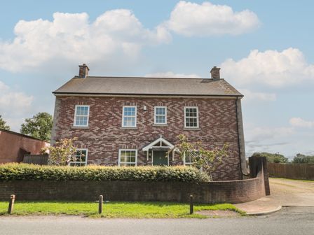 A brick house with a tiled roof and six windows behind a hedge and low brick wall at Cherry Tree House in Highbridge