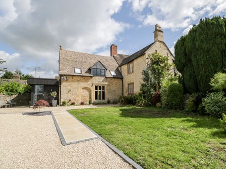 A stone house with a lawn front garden and a gravel driveway at Suncroft in Southam near Prestbury