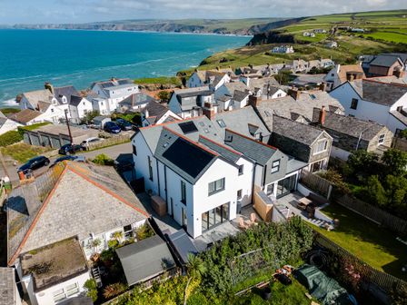A coastal village with houses near the ocean and green hills in the background at 12 Tintagel Terrace in Port Isaac